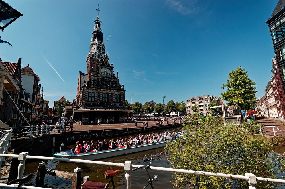 De Waag in Alkmaar gezien vanaf het water, met een rondvaartboot met passagiers ervoor
